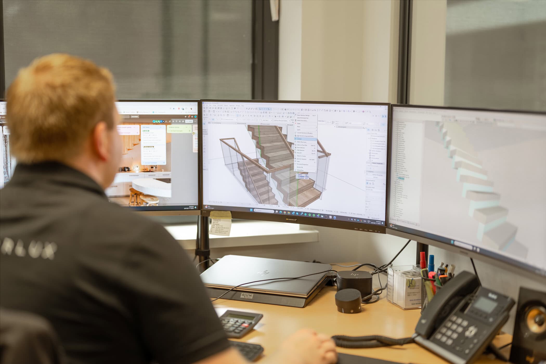 Werkvoorbereider bekijkt 3D-trappenontwerp op drie monitoren in kantoor.